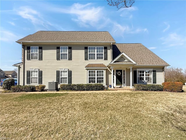 colonial home with a shingled roof, a front yard, and central air condition unit