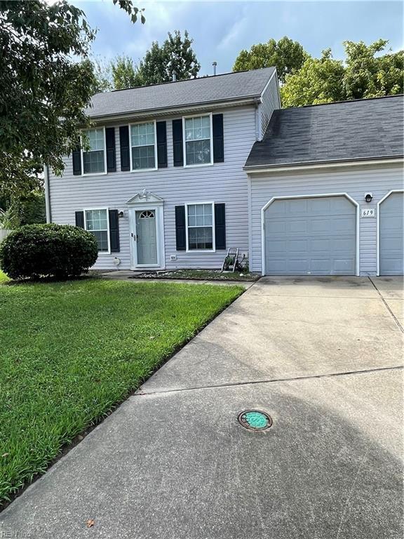 colonial home with a garage, a front lawn, and concrete driveway