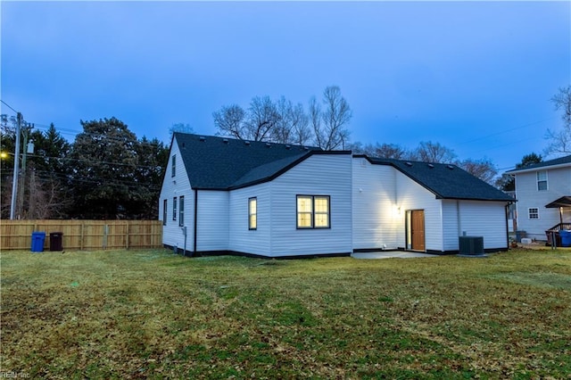 back of property featuring fence, central AC, and a yard