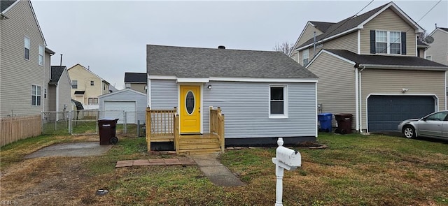 view of front of home featuring a front lawn, roof with shingles, fence, and a gate