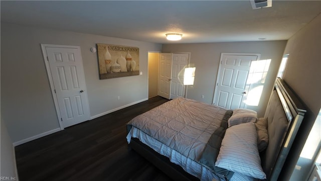 bedroom with dark wood-style flooring, visible vents, and baseboards