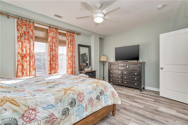 bedroom with light wood-style floors, visible vents, baseboards, and a ceiling fan