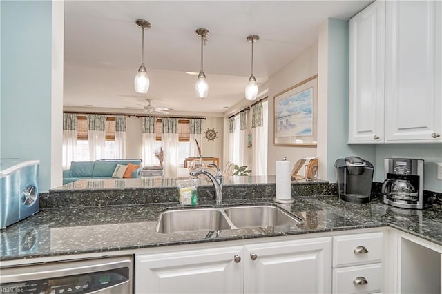 kitchen featuring decorative light fixtures, white cabinetry, a sink, dark stone countertops, and dishwasher