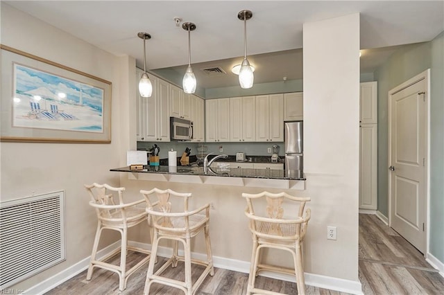 kitchen featuring a peninsula, appliances with stainless steel finishes, a breakfast bar area, and visible vents