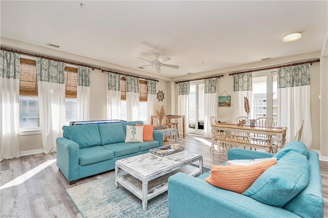 living room with visible vents, ceiling fan, light wood-style flooring, and baseboards