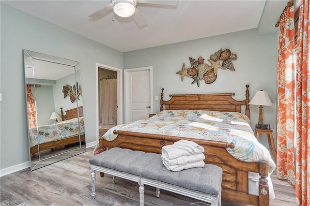 bedroom featuring a ceiling fan, attic access, baseboards, and wood finished floors