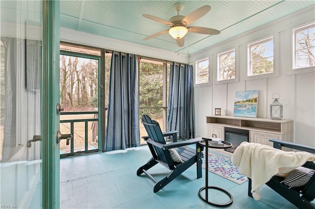 sunroom / solarium with a glass covered fireplace and ceiling fan