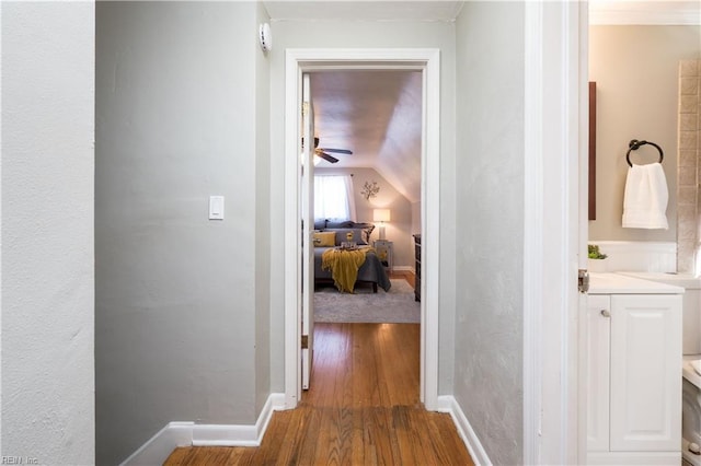 hallway with lofted ceiling, wood finished floors, and baseboards