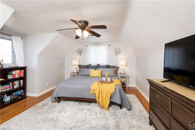 bedroom with lofted ceiling, ceiling fan, light wood-style flooring, and baseboards