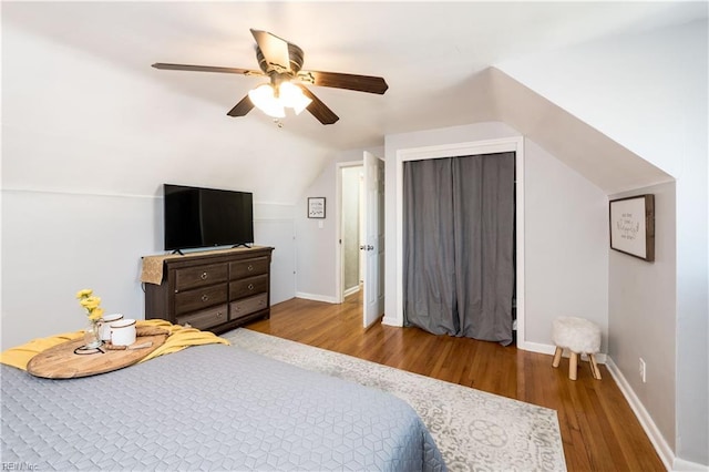 bedroom with lofted ceiling, ceiling fan, baseboards, and wood finished floors