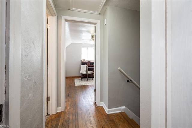 hall with attic access, baseboards, dark wood-style flooring, vaulted ceiling, and an upstairs landing