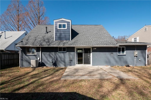 rear view of house with central AC unit, a yard, brick siding, and a patio