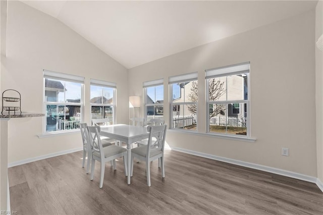 dining space with lofted ceiling, baseboards, and wood finished floors