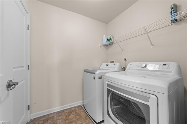 laundry area with laundry area, washing machine and clothes dryer, and baseboards