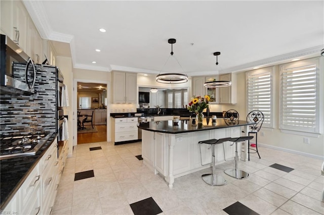 kitchen featuring stainless steel appliances, dark countertops, hanging light fixtures, and ornamental molding