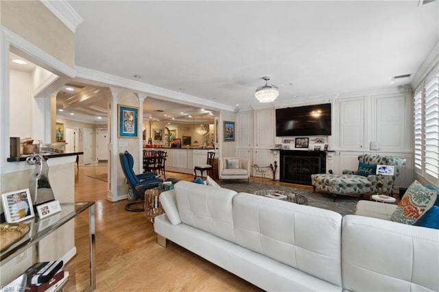 living room with recessed lighting, a fireplace, ornamental molding, light wood-type flooring, and decorative columns