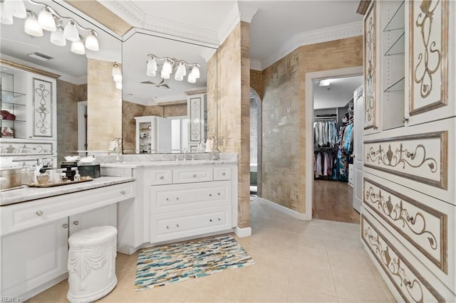 full bath with tile patterned floors, a walk in closet, vanity, and crown molding