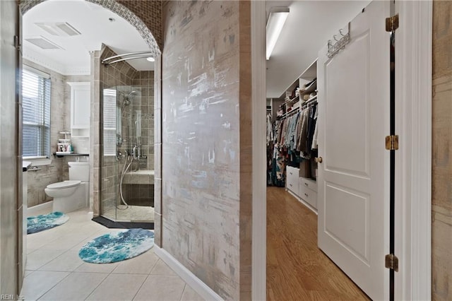 full bath with tile patterned flooring, toilet, a spacious closet, and a shower stall