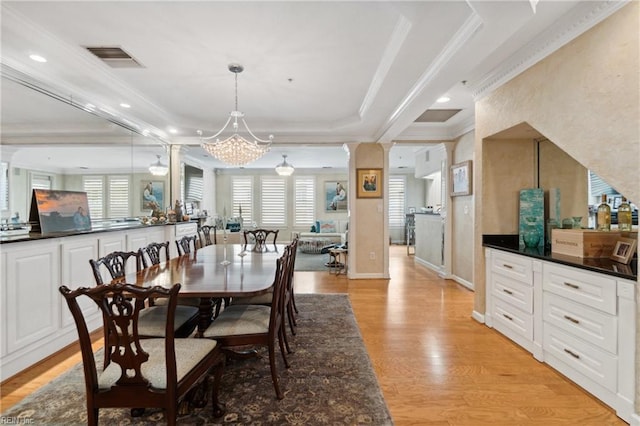 dining room featuring a tray ceiling, a notable chandelier, visible vents, light wood-style floors, and ornamental molding