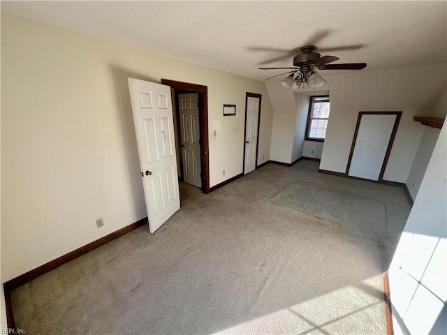 interior space with baseboards, a ceiling fan, and light colored carpet