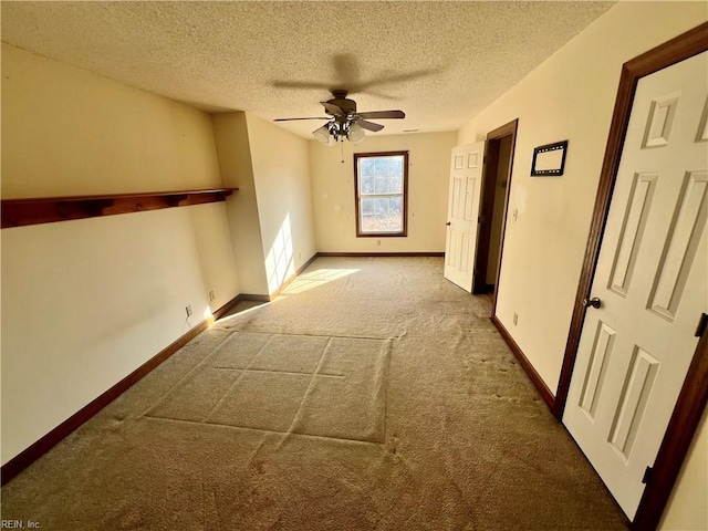 carpeted empty room with a ceiling fan, a textured ceiling, and baseboards