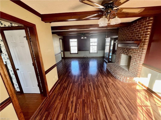 unfurnished living room featuring a textured ceiling, wood finished floors, baseboards, a brick fireplace, and beam ceiling