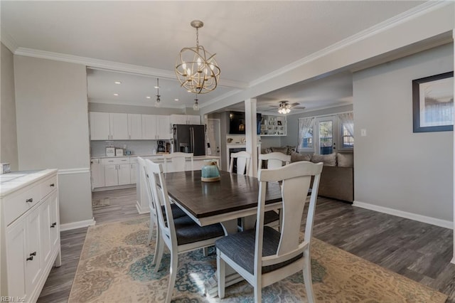 dining area featuring ornamental molding, dark wood-style flooring, baseboards, and ceiling fan with notable chandelier