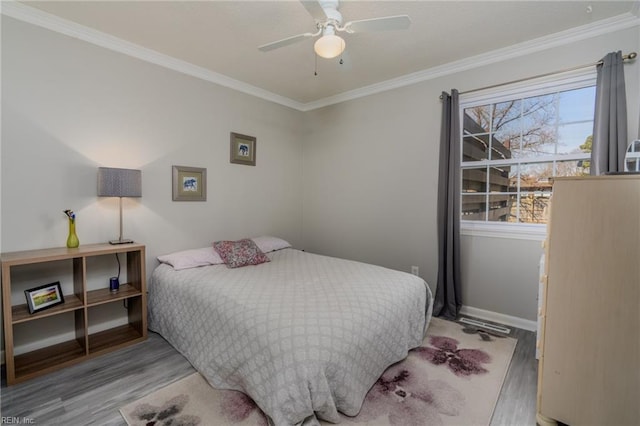 bedroom featuring a ceiling fan, crown molding, baseboards, and wood finished floors