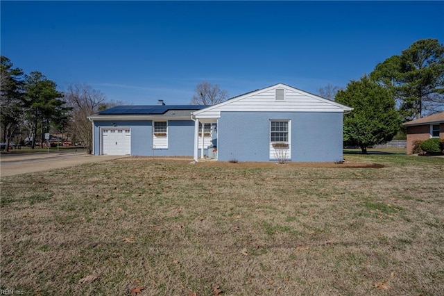 view of front facade with a front lawn, driveway, an attached garage, and solar panels