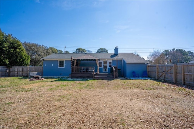 back of property featuring a deck, a yard, an outdoor fire pit, and a fenced backyard