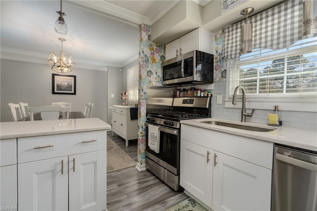 kitchen featuring tasteful backsplash, appliances with stainless steel finishes, ornamental molding, light countertops, and a sink