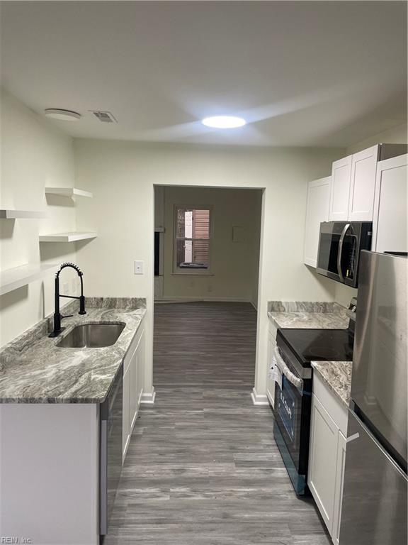 kitchen with visible vents, white cabinets, appliances with stainless steel finishes, stone counters, and a sink