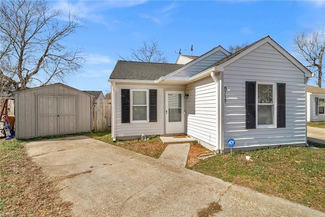 bungalow-style home with a shed, roof with shingles, and an outdoor structure