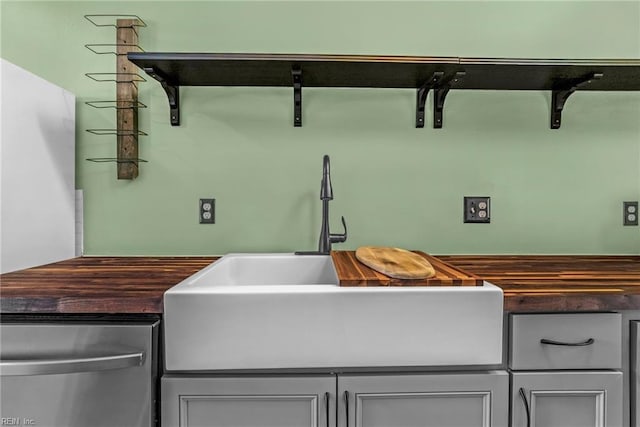 interior space featuring butcher block countertops, gray cabinets, a sink, and dishwasher