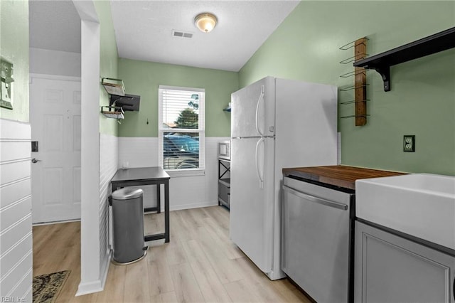 kitchen with visible vents, light wood-type flooring, gray cabinets, freestanding refrigerator, and dishwasher