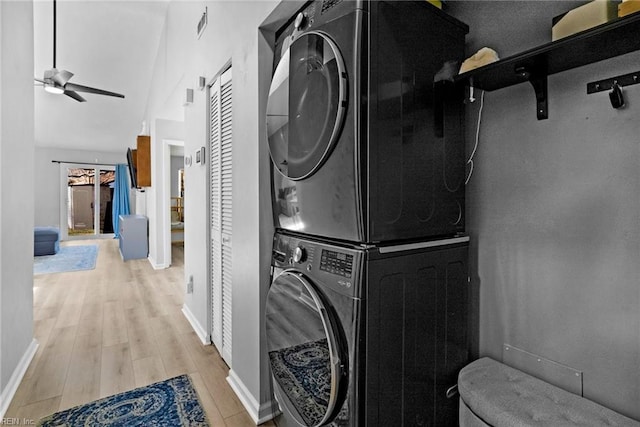 laundry room featuring stacked washer and dryer, laundry area, baseboards, a ceiling fan, and light wood-style flooring