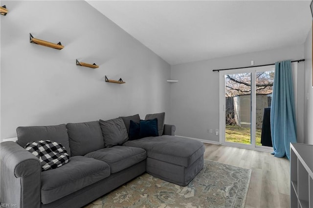 living room with lofted ceiling, light wood-type flooring, and baseboards