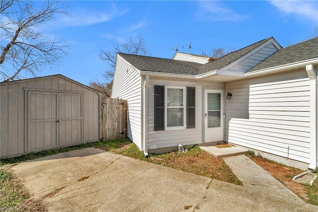 property entrance with a shingled roof, fence, and a patio