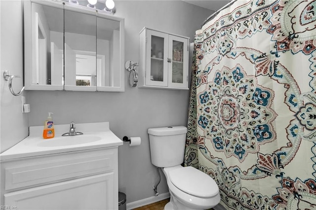 bathroom with curtained shower, baseboards, vanity, and toilet