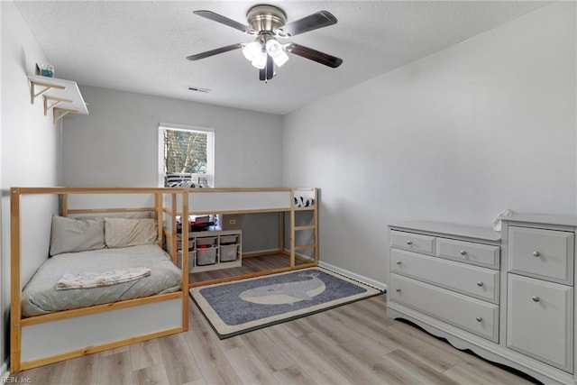 bedroom featuring visible vents, ceiling fan, a textured ceiling, and wood finished floors