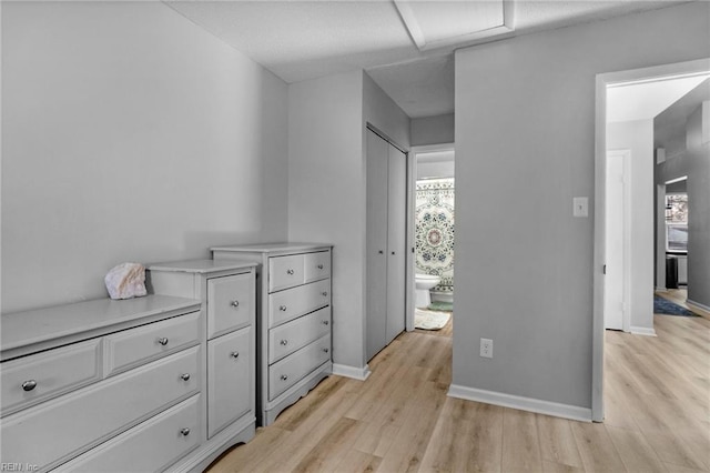 bedroom featuring light wood-style floors, baseboards, and connected bathroom