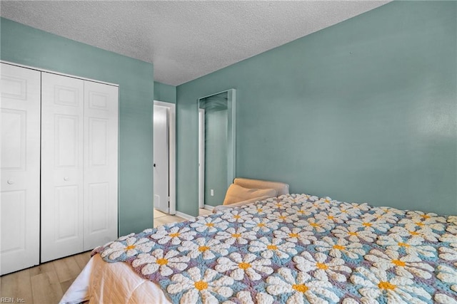 bedroom with a textured ceiling, a closet, and wood finished floors