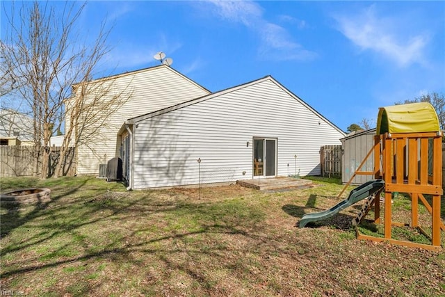 back of house featuring a yard, a playground, and fence