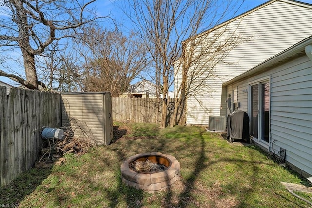 view of yard featuring an outdoor fire pit, a fenced backyard, and central air condition unit