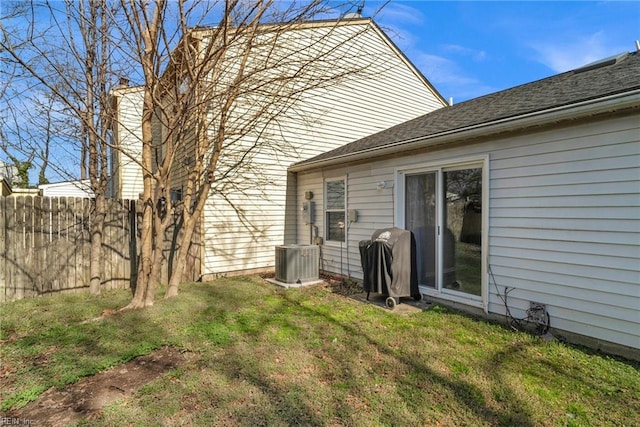 back of property with a lawn, fence, and central AC unit