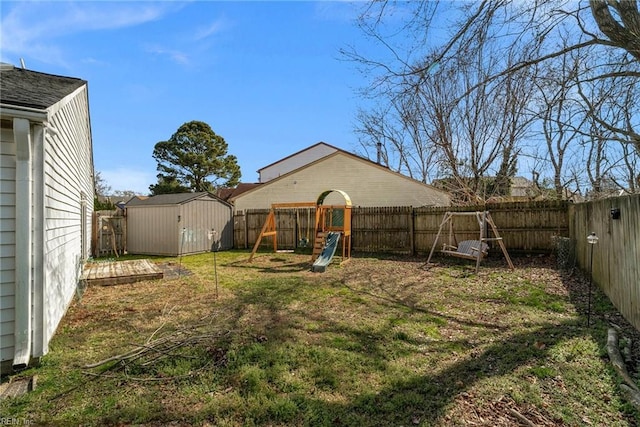 view of yard featuring an outbuilding, a storage unit, a playground, and a fenced backyard