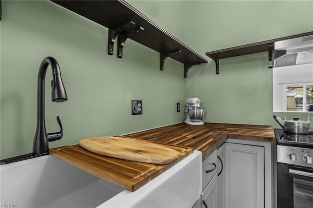 kitchen featuring wall oven, white cabinets, wood counters, open shelves, and a sink