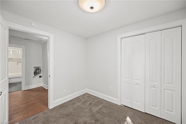 unfurnished bedroom with a closet, carpet, attic access, and baseboards