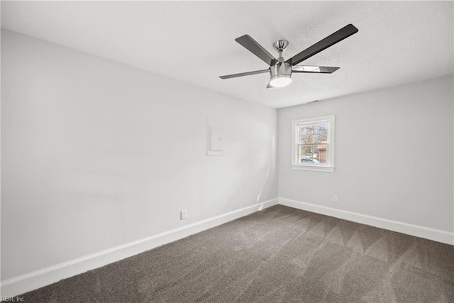 empty room featuring a textured ceiling, dark colored carpet, a ceiling fan, and baseboards