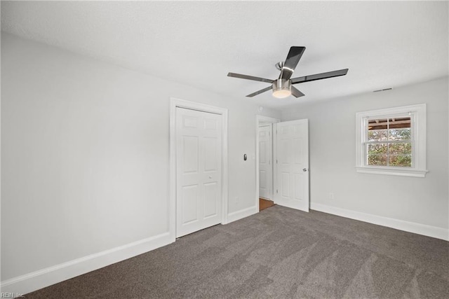 unfurnished bedroom featuring visible vents, baseboards, ceiling fan, dark colored carpet, and a closet